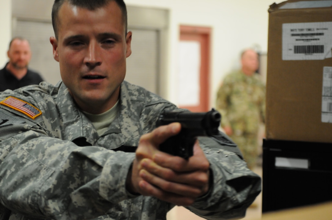 Staff Sgt. John Pudowski, the master driver in the 416th Theater Engineer Command (TEC) and police officer in the Chicago police department, reacts to a scenario, during active shooter training held at the TEC headquarters in Darien, Ill. The training provided by Special Agent Culloton gave Soldiers tools to react and protect themselves in an active shooter situation, Aug. 6, 2016. (U.S. Army photo by Spc. Brianna Saville/Released)