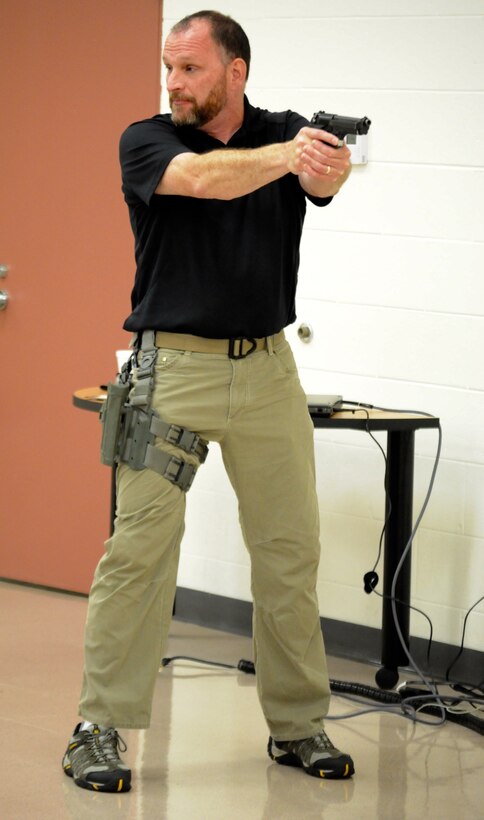 FBI Special Agent Michael Culloton demonstrates proper pistol handling and drawing techniques during Active shooter training at 416th Theater Engineer Command Headquarters, in Darien, Ill. The training provided by Special Agent Culloton gave Soldiers tools to react and protect themselves in an active shooter situation, Aug. 6, 2016. (U.S. Army photo by Spc. Brianna Saville/Released)