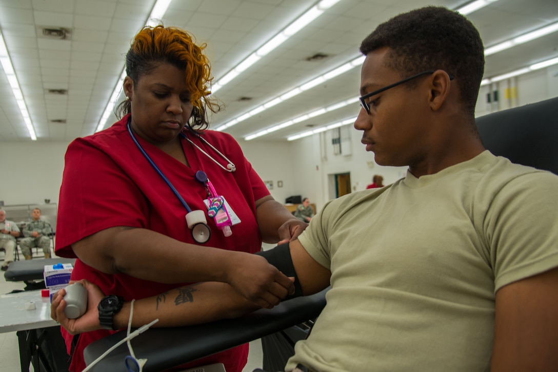 Felicia Taylor, American Red Cross phlebotomist collection technician three, prepares Spc. Curtis Smith, 335th Transportation Detachment watercraft operator, to donate blood during a blood drive at Fort Eustis, Va., August 3, 2016. Whole blood donation is the most common type, during which approximately a pint of whole blood is given. (U.S. Air Force photo by Staff Sgt. J.D. Strong II)