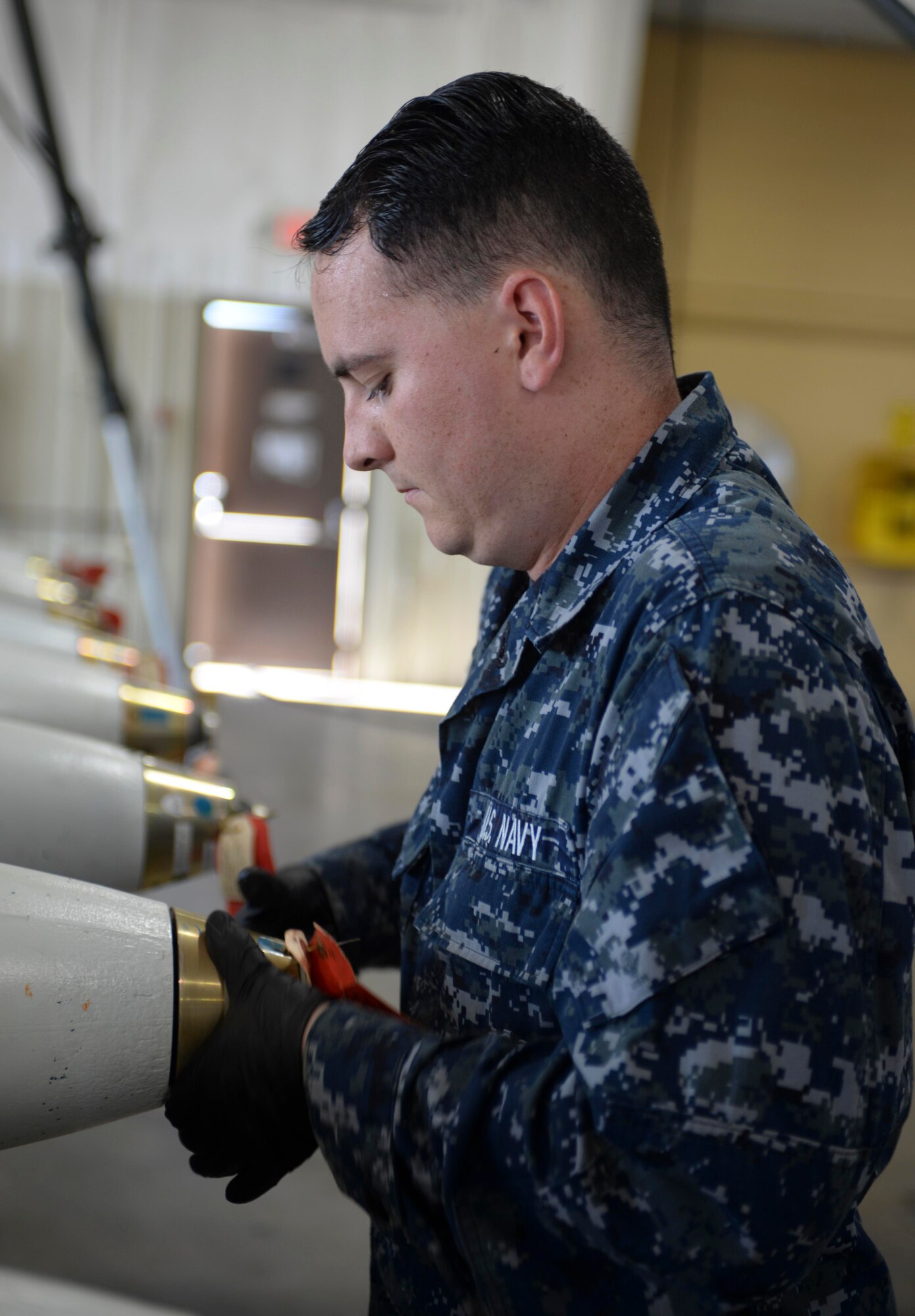 Seaman Mathew King, a mineman assigned to the Navy Munitions Command Atlantic Unit, Charleston, S.C., screws on a lid to an inert MK 62 mine at Ellsworth Air Force Base, S.D., July 20, 2016. Upon impact, the tip will split and pull on a lanyard connected to a pin to start the arming process. (U.S. Air Force photo by Airman 1st Class Sadie Colbert)