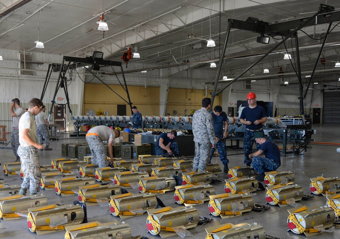 Service members work together to craft mines at Ellsworth Air Force Base, S.D., July 20, 2016. Sailors from the Navy Munitions Command Atlantic Unit, Charleston, S.C., helped Airmen build inert MK 62 mines which can be loaded into B-1 bombers to deploy during training sorties, and have the capability to guide themselves into the targeted area. (U.S. Air Force photo by Airman 1st Class Sadie Colbert)