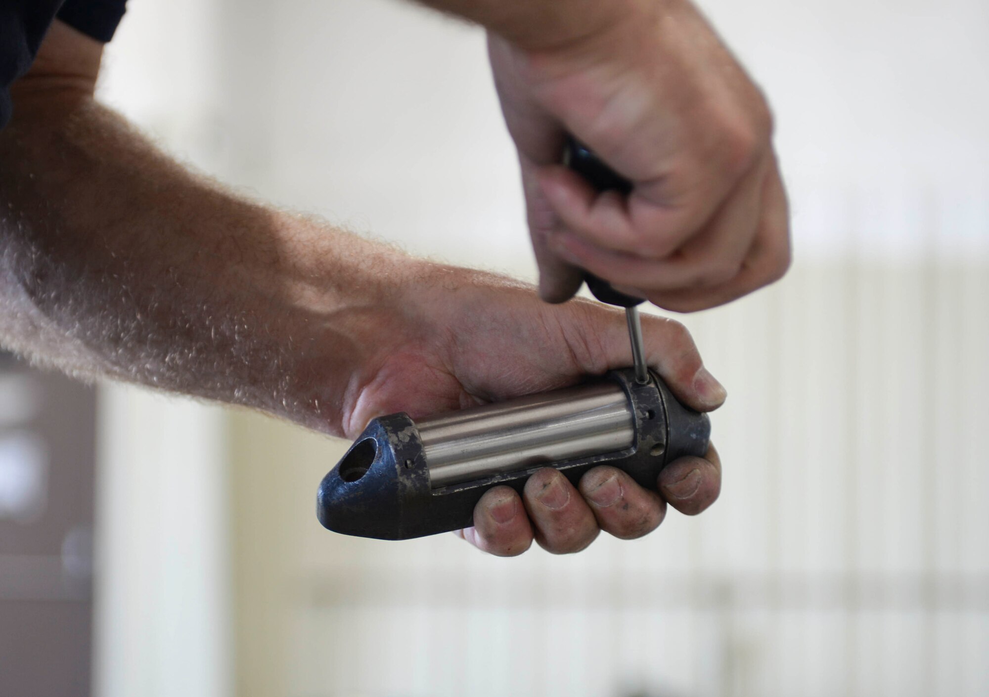 A Sailor assigned to the Navy Munitions Command Atlantic Unit Charleston, S.C., attaches a pinging mechanism to a case to be attached to an inert MK 62 mine at Ellsworth Air Force Base , S.D., July 20, 2016. Once the mine has deployed, the piece will send out a transmission signal so Navy personnel can recover the training munition. (U.S. Air Force photo by Airman 1st Class Sadie Colbert)