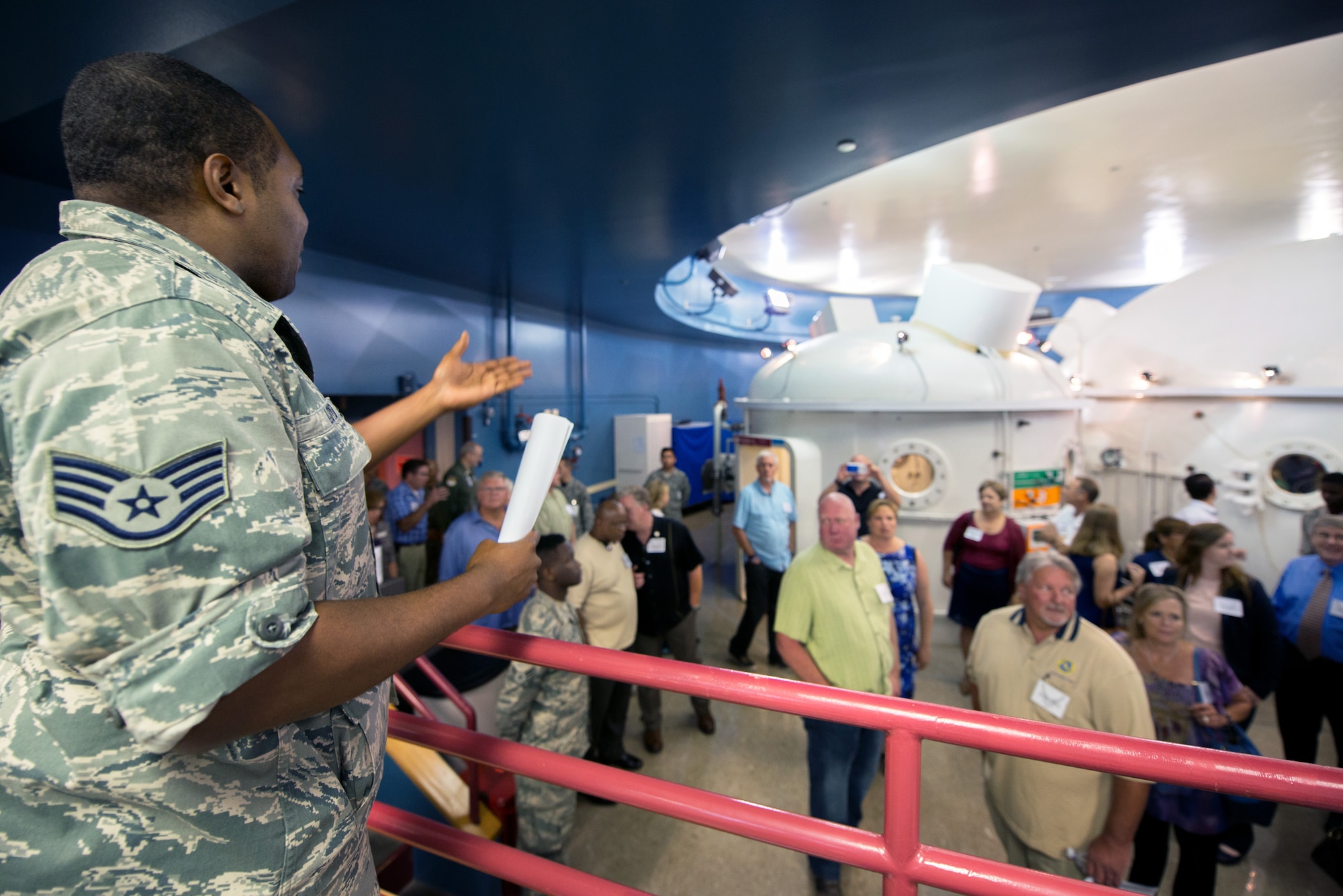 U.S. Air Force Staff Sgt. Michael Lloyd, 60th Aerospace Medicine Squadron NCOIC hyperbaric chamber clinic, briefs honorary commanders on the hyperbaric multiplace chamber during their tour of David Grant USAF Medical Center at Travis Air Force Base, Calif., July 29, 2016. (U.S. Air Force photo by Louis Briscese)
