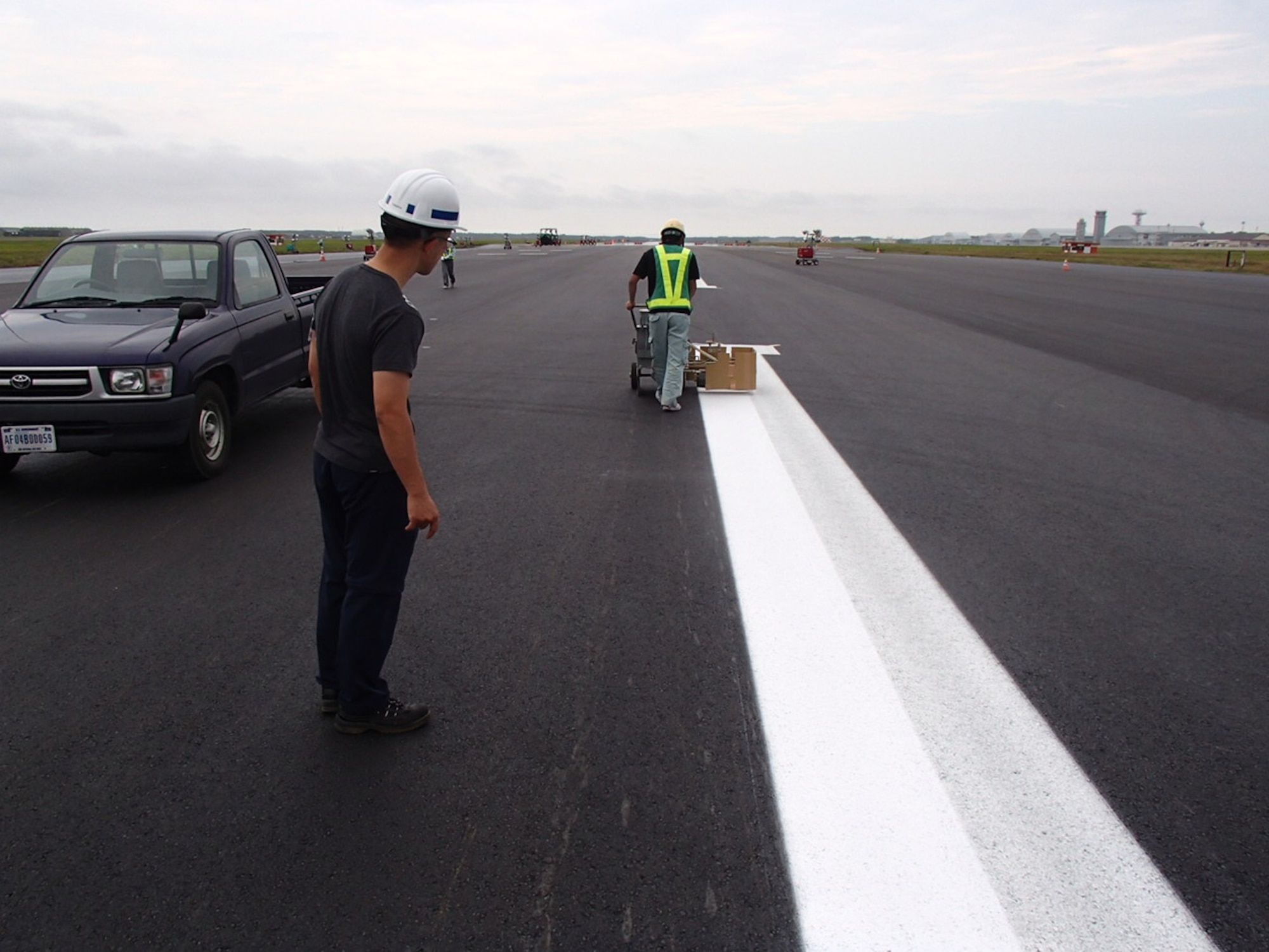 Civil engineering crews mark the runway at Misawa Air Base, Japan, July 31, 2016. The project cost more than $2.1 million, using four milling machines, two pavers, 76 dump trucks and approximately 80 on-site personnel, ultimately enhancing the longevity of the runway. (Courtesy photo)