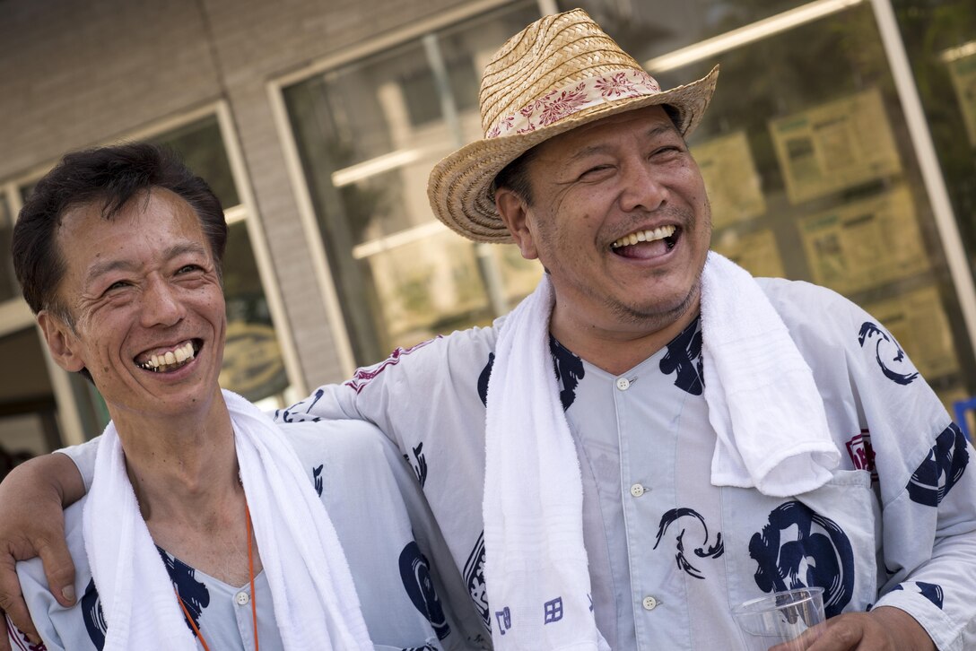 Men watch people carry mikoshis, or portable shrines, down a road in Fussa City, Japan, Aug. 5, 2016, during the 66th Annual Fussa Tanabata Festival. Every year, Fussa, a city neighboring Yokota Air Base, hosts the Tanabata, or Star Festival. (U.S. Air Force photo by Staff Sgt. Cody H. Ramirez/Released)
