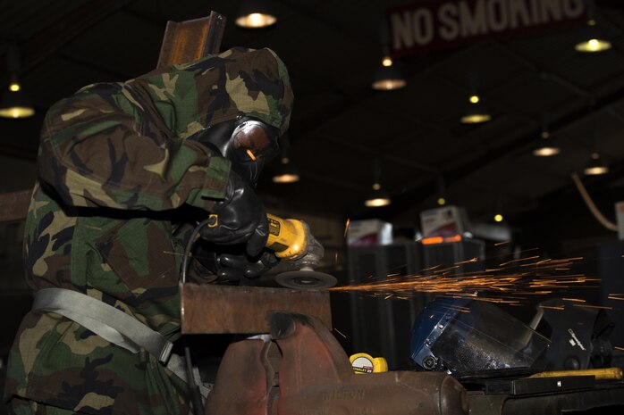 U.S. Marine Corps Lance Cpl. Trevon Bruce, a metal worker with Combat Logistics Company 36, grinds steel during chemical, biological, radiological and nuclear defense training at Marine Corps Air Station Iwakuni, Japan, Aug. 10, 2016. Marines, already in mission oriented protective posture gear, were evaluated on their ability to effectively detect, report, respond and operate in a simulated CBRN environment. When given the signal “gas, gas, gas,” Marines scrambled to don their M50 Joint Service General Purpose Masks before returning to work as if everything was normal.  (U.S. Marine Corps photo by Lance Cpl. Joseph Abrego)