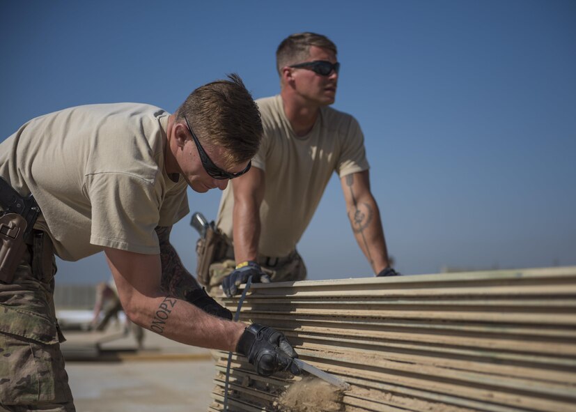 Senior Airman Seth Lindquist, 455th Expeditionary Civil Engineer Squadron operations management technician, removes dirt from a piece of AM-2 aluminum matting, Bagram Airfield, Afghanistan, Aug. 11, 2016. Dirt and debris must be cleared off of the matting to ensure it lays flat and fits into the spacing. (U.S. Air Force photo by Senior Airman Justyn M. Freeman)