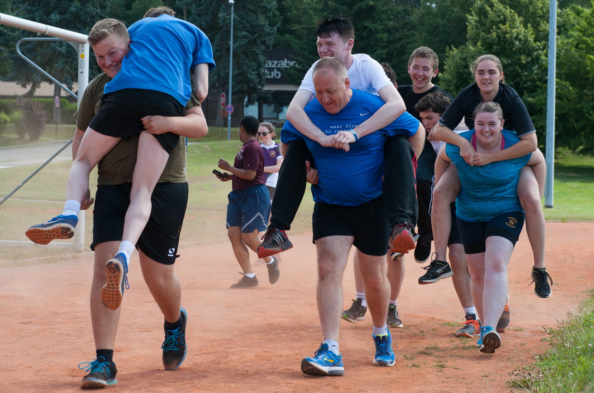 Royal Air Force cadets race down a dirt track performing fireman carries during Warrior Day, a physical exercise regimen hosted by the NCO Academy Aug. 8, at Vogelweh Military Complex, Germany. Warrior Day is a mentorship program between the Air Force and the United Kingdom, where NCOA cadre provide insight on how Airmen train and stay educated.  The event served as a way of allowing the countries to strengthen their relationship. (U.S. Air force photo/Airman 1st Class Lane T. Plummer)