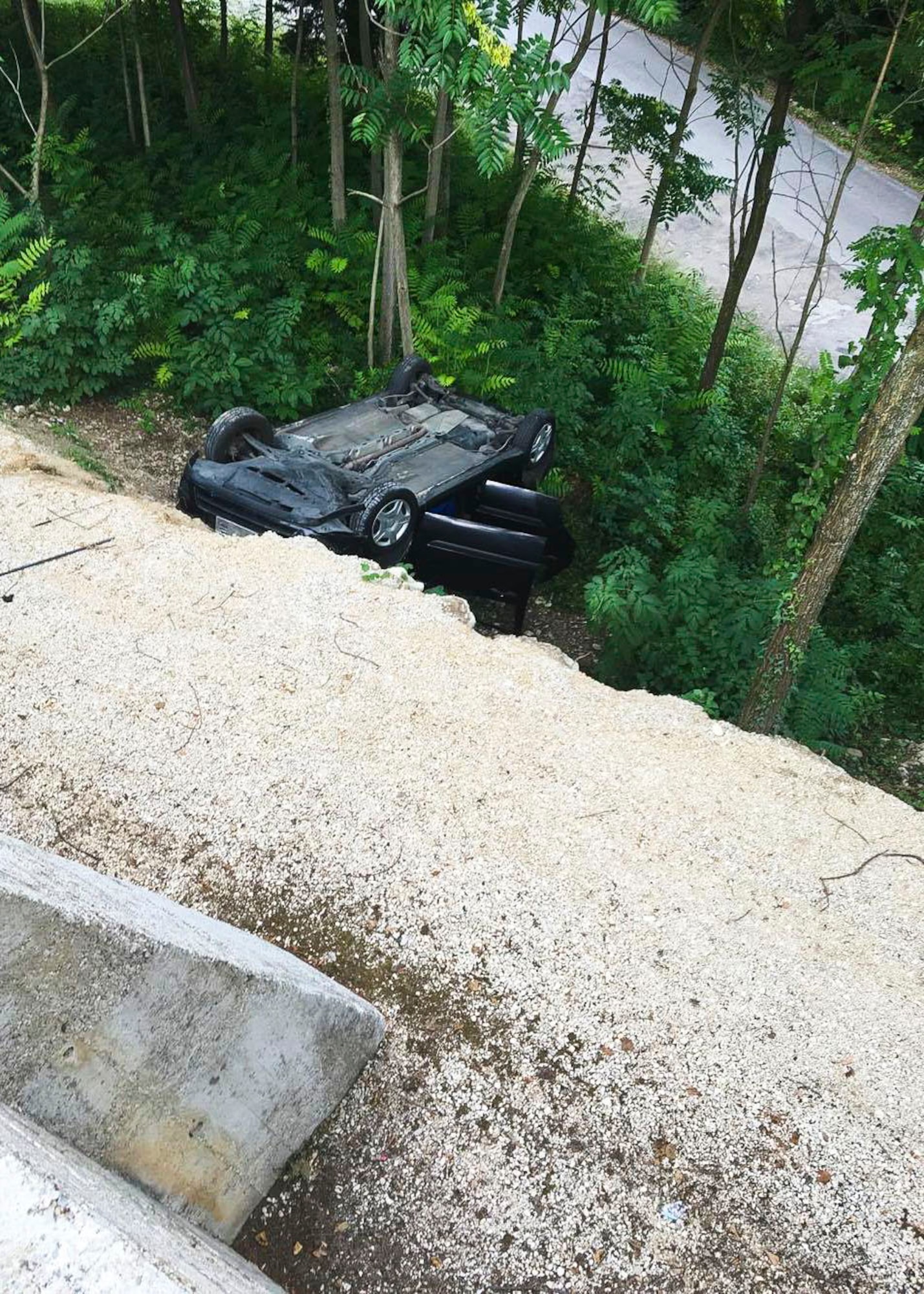 A car lies upside down in a ditch after two 31st Logistics Readiness Squadron Airmen rescue its passengers, July 9, 2016, in Costa di Aviano, Italy. The car broke through a fenced parking lot approximately 30 feet up from the crash site with two passengers inside. (Courtesy photo/Jessica Reed)