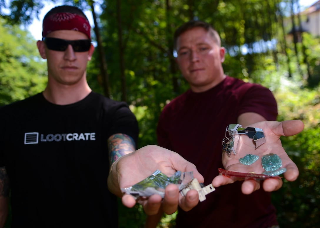 (From left) Senior Airmen Jeff Oberschlake and Robert Johnson, 31st Logistics Readiness Squadron vehicular equipment maintenance journeymen, hold debris from a car crash, Aug. 7, 2016, in Costa di Aviano, Italy. A month earlier, the two Airmen saved two passengers from the crushed car that produced the debris. (U.S. Air Force photo by Senior Airman Austin Harvill/Released)