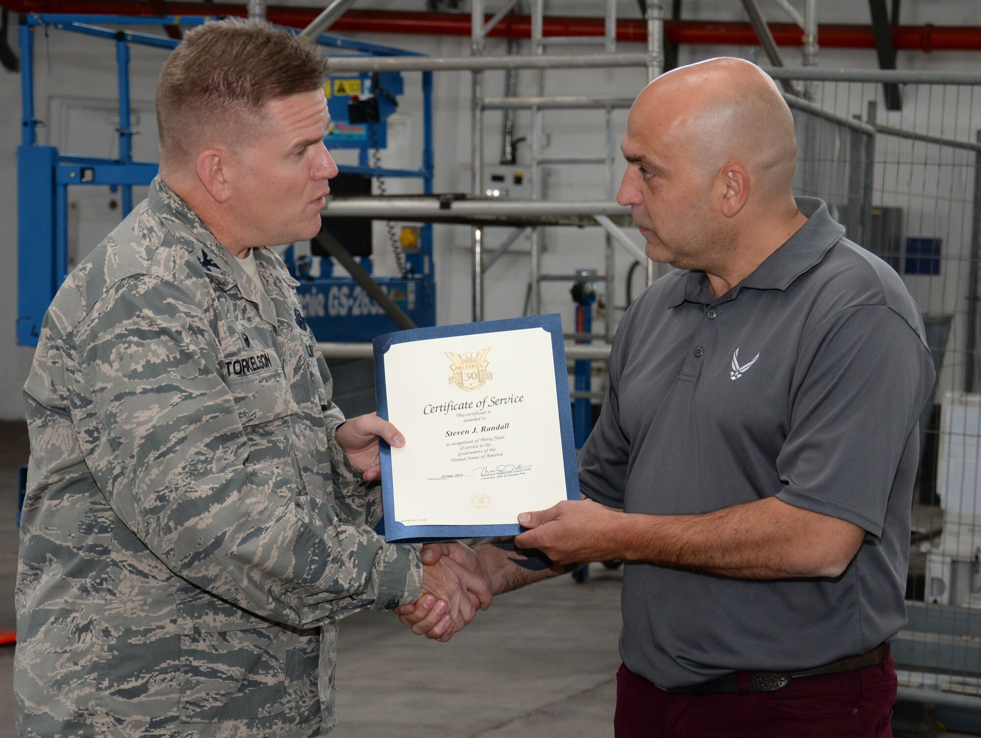 Steven Randall, right, 100th Logistics Readiness Squadron distribution manager, receives a certificate of service from U.S. Air Force Col. Thomas Torkelson, 100th Air Refueling Wing commander,  Aug. 10, 2016, on RAF Mildenhall, England. Randall began working on RAF Lakenheath in 1986 as a Commissary worker. (U.S. Air Force photo by Gina Randall)