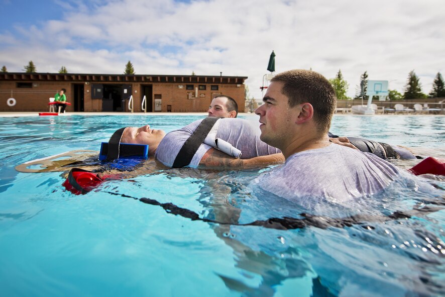 Airmen from the 5th Medical Operations Squadron move a simulated patient during training at the base pool at Minot Air Force Base, N.D., Aug. 10, 2016. A water rescue board is used in conjunction with lifeguard buoys to keep the patient above water during the rescue. (U.S. Air Force photo/Airman 1st Class J.T. Armstrong)