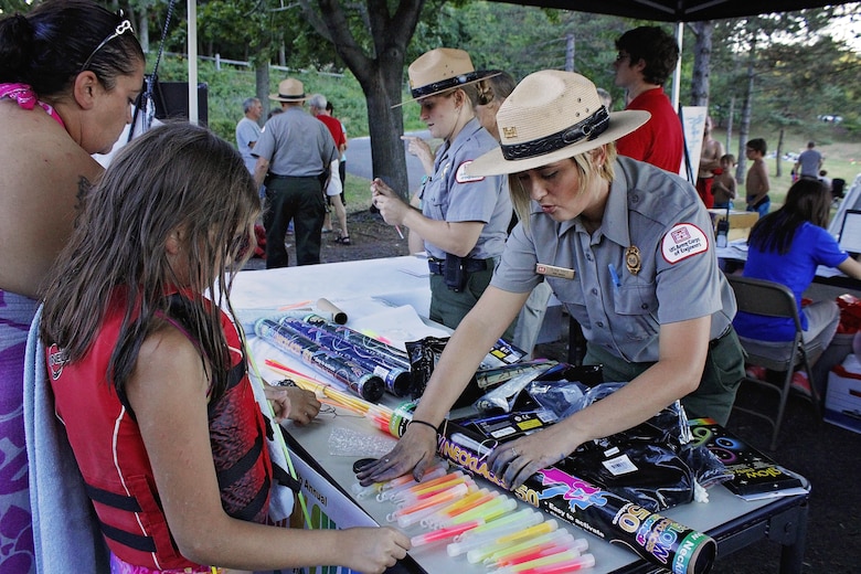 Olivia Mays, park ranger, U.S. Army Corps of Engineers, Raystown Lake, hands out glow sticks to participants of the 4th annual Glow Swim at Seven Points Beach, Aug. 6, 2016. 