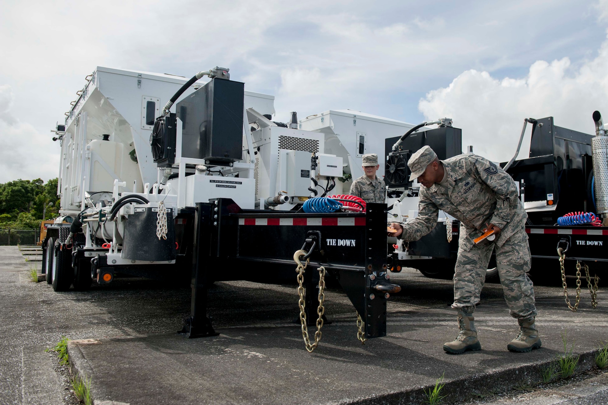 Tech. Sgt. Michael Greene, 18th Logistics Readiness Squadron fleet management and analysis assistant NCO in charge, and Airman 1st Class Quentin Isenberg, 18th LRS FMA analysis apprentice, check pile tags on new volume mixers Aug. 11, 2016, at Kadena Air Base, Japan. Greene and Isenberg inspect all incoming vehicle fleet equipment for any damage or leaks prior to uploading equipment profiles to tracking systems. (U.S. Air Force photo by Senior Airman Peter Reft)