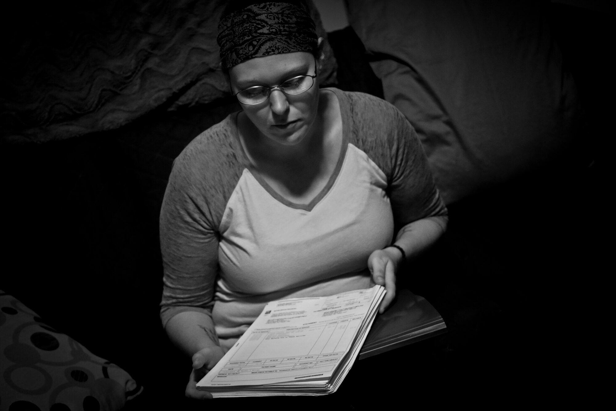 Rachel Miller, 30, looks at a stack of unpaid medical bills, July 19, 2016. Miller and her boyfriend Matt Nichol are both on disability, and live in a small one bedroom apartment in Cortland, N.Y. Nearly one in three residents of Cortland are at or below the poverty line. Miller and Nichol attended the Healthy Cortland Innovative Readiness Training event aimed at Cortland residents, which included military service members providing no cost medical, dental, optometry, and veterinary care. (U.S. Air National Guard photo by Tech. Sgt. Matt Hecht/Released)