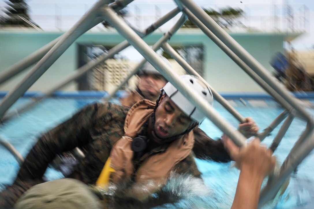 Marines flip over Marine Corps Sgt. W. L. McMullen, foreground, in the shallow water egress training chair at Camp Hanse in Okinawa, Japan, Aug. 10, 2016. McMullen is assigned to the 3rd Marine Expeditionary Brigade. Marine Corps photo by Sgt. Ally Beiswanger