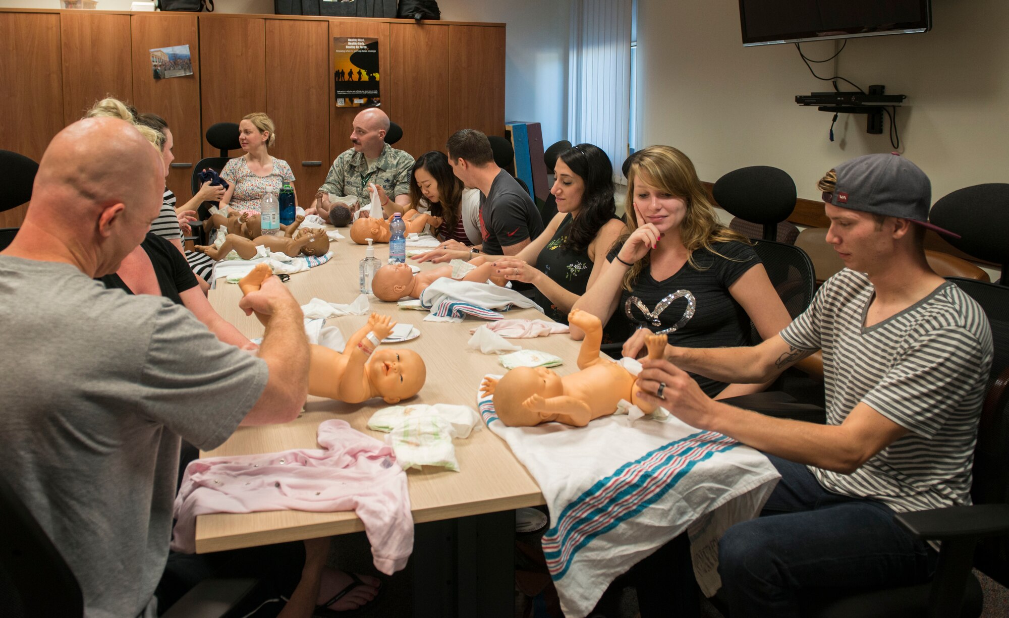 Baby Basic Training participants practice changing a diaper on August 4, 2016, at Aviano Air Base, Italy. The two-part class teaches expecting parents about basic care and safety for infants, child development and the importance of breastfeeding. (U.S. Air Force photo by Senior Airman Krystal Ardrey/Released)