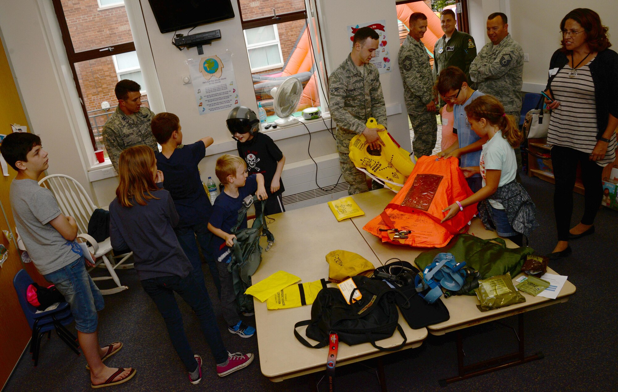 Guests of the Hearts Apart event, hosted by the 351st Air Refueling Squadron, and are given the chance to try on various equipment utilized by aircrew Aug. 12, 2016, at the base chapel on RAF Mildenhall, England. The event is held monthly to bring families of deployed military members together to participate in dinner and activities. (U.S. Air Force photo by Senior Airman Justine Rho)