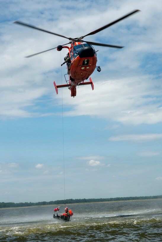 A Coast Guard H-65 Dolphin helicopter hoists an airman in a basket during water survival training at Bowers Beach, Del., Aug. 6, 2016. Air Force photo by Tech. Sgt. Nathan Rivard