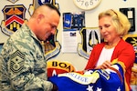 Caruso, U.S. Transportation Command senior enlisted leader, examines an Air War College flag with Linda Farrell, a fabric worker, at the flag room during a visit to DLA Troop Support Aug. 10.