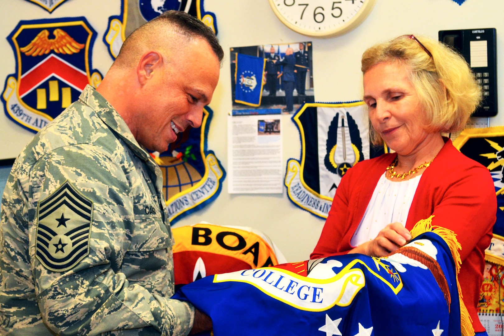 Caruso, U.S. Transportation Command senior enlisted leader, examines an Air War College flag with Linda Farrell, a fabric worker, at the flag room during a visit to DLA Troop Support Aug. 10.