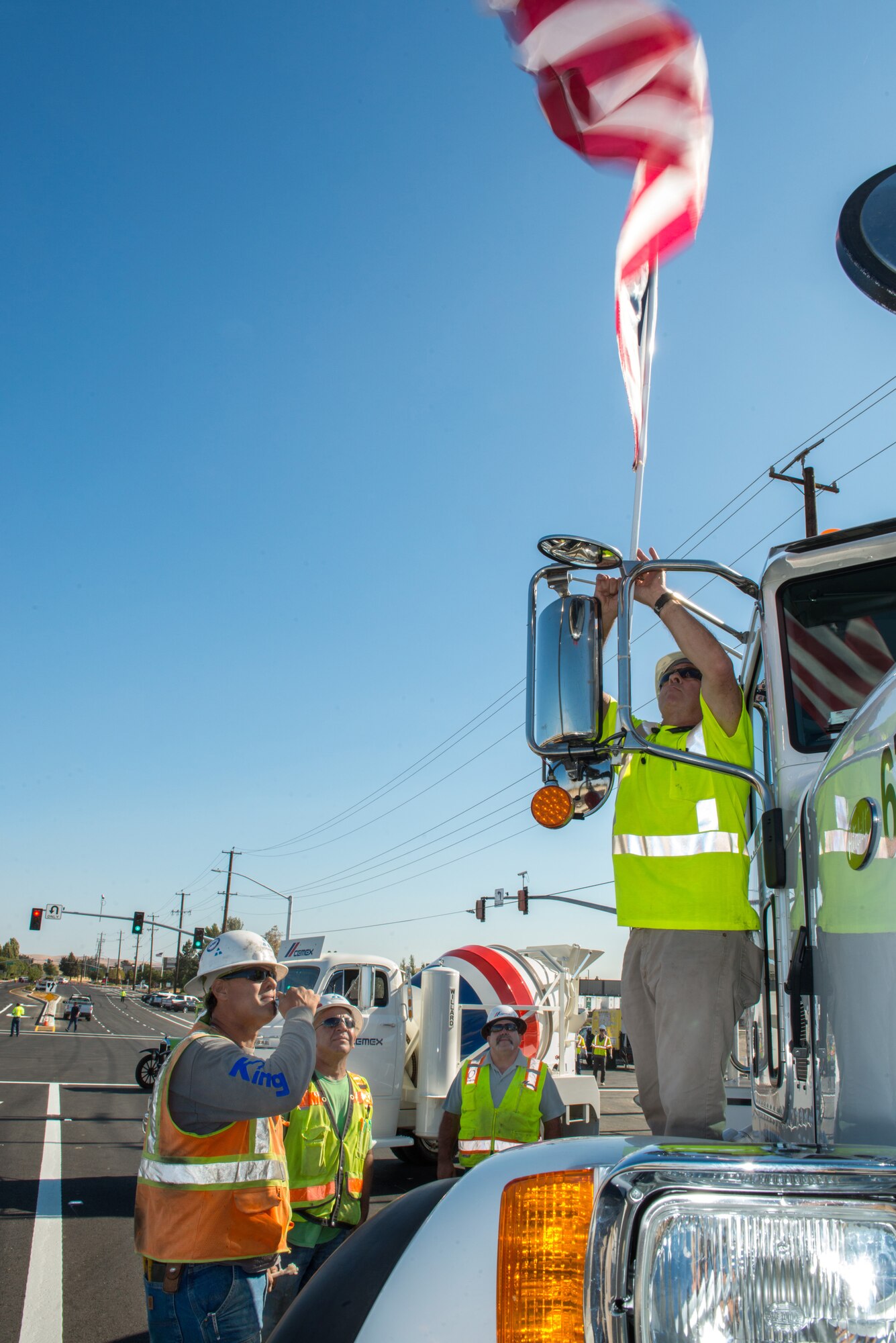 Steve Alexander, area manager for Cemex, and Bart White, construction foreman for Teichert erect the flag prior to the Peabody Road reopening ceremony in Fairfield, Calif., Aug. 4, 2016. The road was closed for 14-months and finished ten days ahead of schedule. Peabody Road is a major thoroughfare that connects the cities of Vacaville and Fairfield, more than 20,000 vehicles per day use the road and it is also a major artery into Travis Air Force Base for more than 14,000 employees. The construction of the Peabody Road overpass is part of the new Fairfield-Vacaville train station project along the Capitol Corridor. (U.S. Air Force photo by Louis Briscese) 