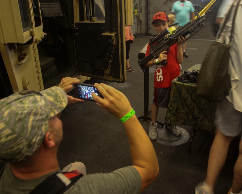 A local resident poses with a Marine Corps M249 squad automatic weapon that was part of a static display aboard the USS Oak Hill (LSD-51) during Lobster Fest in Rockland, ME, Aug. 5, 2016. The Marines and Sailors with Combat Logistics Battalion 8, 2nd Marine Logistics Group, aboard the USS Oak Hill, were in port Aug. 3-7 to participate in the festival and display the expeditionary capabilities of the Navy-Marine Corps team. (U.S. Marine Corps photo by Sgt. Olivia McDonald)