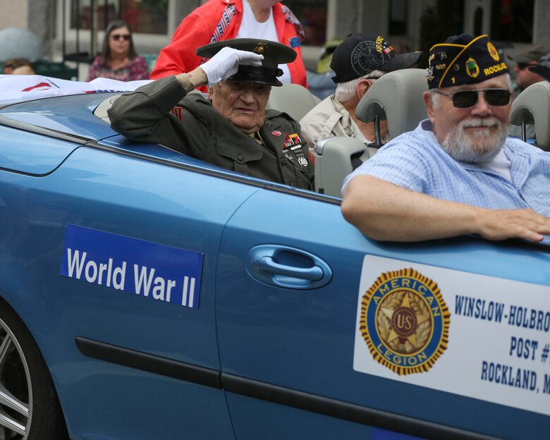 Retired Marine Sgt. Leory Peasley (left), an Iwo Jima veteran, salutes the crowd during the Lobster Fest parade in Rockland, ME, Aug. 6, 2016. Marines and Sailors with Combat Logistics Battalion 8, 2nd Marine Logistics Group, also participated in the parade while in port. The battalion aboard the USS Oak Hill (LSD-51) spent Aug. 3-7 participating in the festival and displaying the expeditionary capabilities of the Navy-Marine Corps team. (U.S. Marine Corps photo by Sgt. Olivia McDonald)