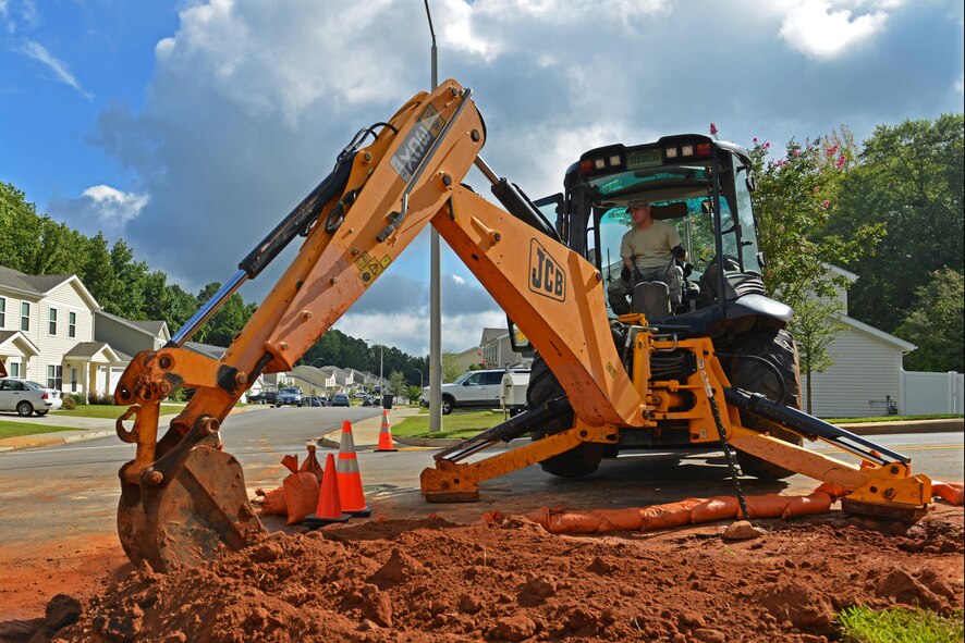 U.S. Air Force Tech. Sgt. Jamie Davis, 20th Civil Engineer Squadron heavy equipment craftsman, fills a hole with dirt using a backhoe at Shaw Air Force Base, S.C., Aug. 12, 2016. After a water main broke in base housing, the 20th CES excavated, repaired, and refilled the area restoring water to approximately 418 families. (U.S. Air Force photo by Airman 1st Class Destinee Sweeney)