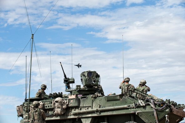 Soldiers from the 1st Armored Division, 1st Stryker Brigade Combat Team, Fort Bliss, Texas, look on as an F-16 Fighting Falcon executes a “show of force” in the skies over the National Training Center Range, Fort Irwin, Calif., during a Green Flag 15-08 training scenario June 12, 2015. In many situations, an aircraft executing a low pass over a conflict zone can act as a deterrent to potential enemy combatants. (U.S. Air Force photo by Senior Airman Joshua Kleinholz)
