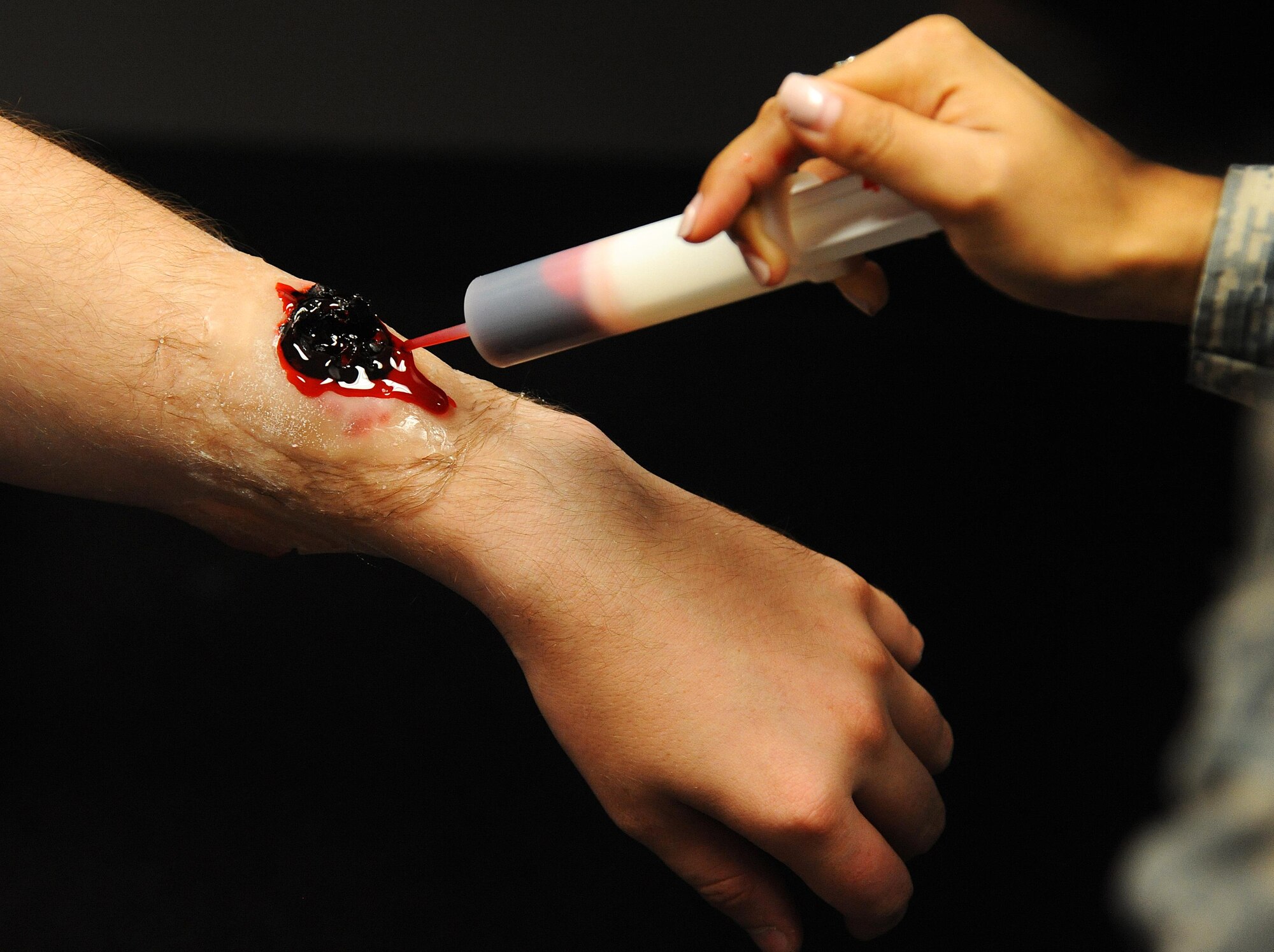 U.S. Air Force Senior Airman Robyn Martinez, a 509th Medical Operations Squadron mental health technician, makes a simulated wound on an exercise player before an active shooter exercise at Whiteman Air Force Base, Mo., Aug. 5, 2016. A variety of moulage wounds were put on “victims” of the exercise in order to help the first responders decide how, and in which order, patients should be treated. 