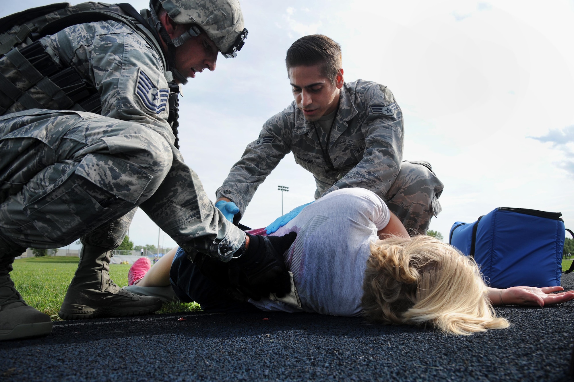 U.S. Air Force Tech. Sgt. Jonathan Arnio, a 509th Security Forces Squadron assistant NCO in charge of training, left, and Senior Airman Zachary Williams, a 509th Medical Operations Squadron aerospace medical technician, right, examine a victim for a simulated wound during an active shooter exercise at Whiteman Air Force Base, Mo., Aug. 5, 2016. Whiteman hosts an active shooter exercise bi-annually to raise awareness for first responders and all of Team Whiteman on how to react in case of a real-life active shooter incident. 