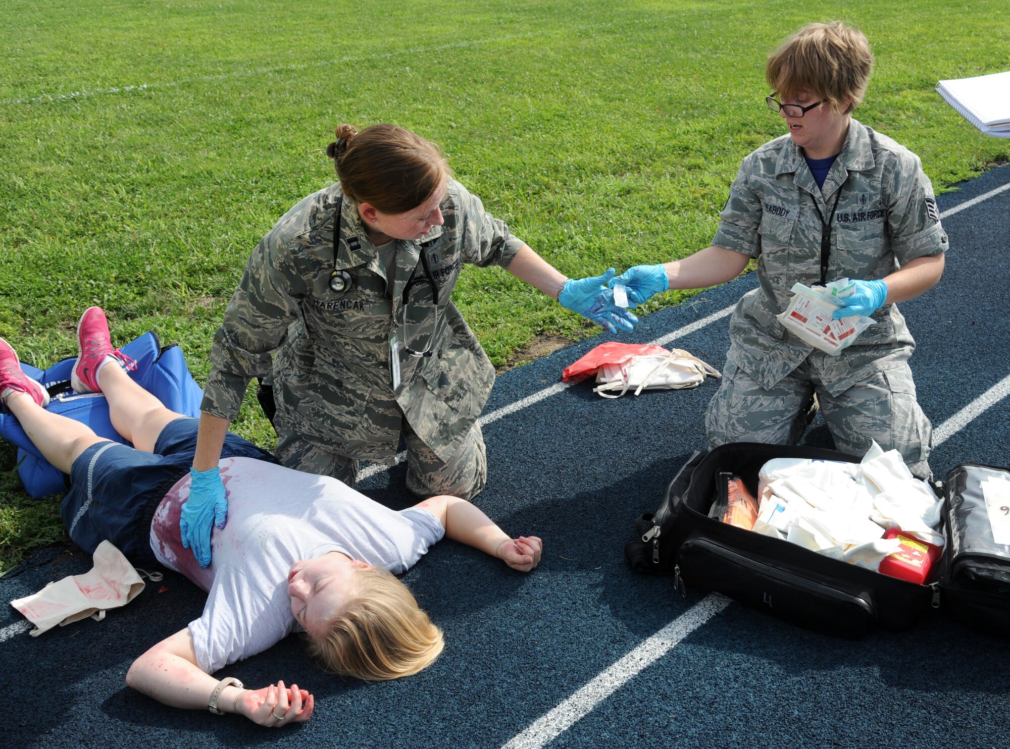U.S. Air Force Staff Sgt. Christina Peabody, a 509th Medical Operations Squadron (MDOS) flight medicine technician, right, hands medication to Capt. Kallyn Harencak, a 509th MDOS flight surgeon, center, to treat a victim’s simulated abdominal injury during an active shooter exercise at Whiteman Air Force Base, Mo., Aug. 5, 2016. The medical technicians treated simulated wounds on the spot during the exercise, then triaged for further care. 