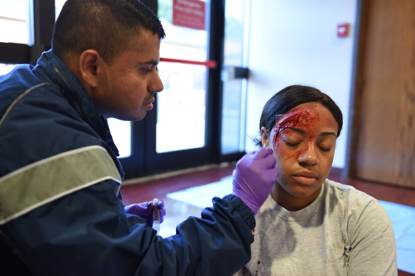 Senior Airman Harsh Vaidya, 779th Medical Operational Squadron aerospace medical technician, applies fake blood to a synthetic wound on Staff Sgt. Erica Frazier, 1st Helicopter Squadron aviation research manager, for the Major Accident Response Exercise at Joint Base Andrews, Md., Aug. 11, 2016. The MARE is an annual training requirement for a base to test its readiness and response capabilities. (U.S. Air Force photo by Senior Airman Joshua R. M. Dewberry)