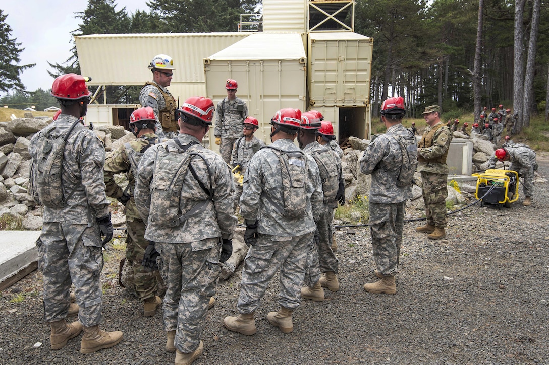 Soldiers and airmen listen to an evaluator explain how to saw through piles of cement rubble after a simulated chemical attack during a joint exercise evaluation at Camp Rilea in Warrenton, Ore., Aug. 2, 2016. Air National Guard photo by Staff Sgt. Bobbie Reynolds