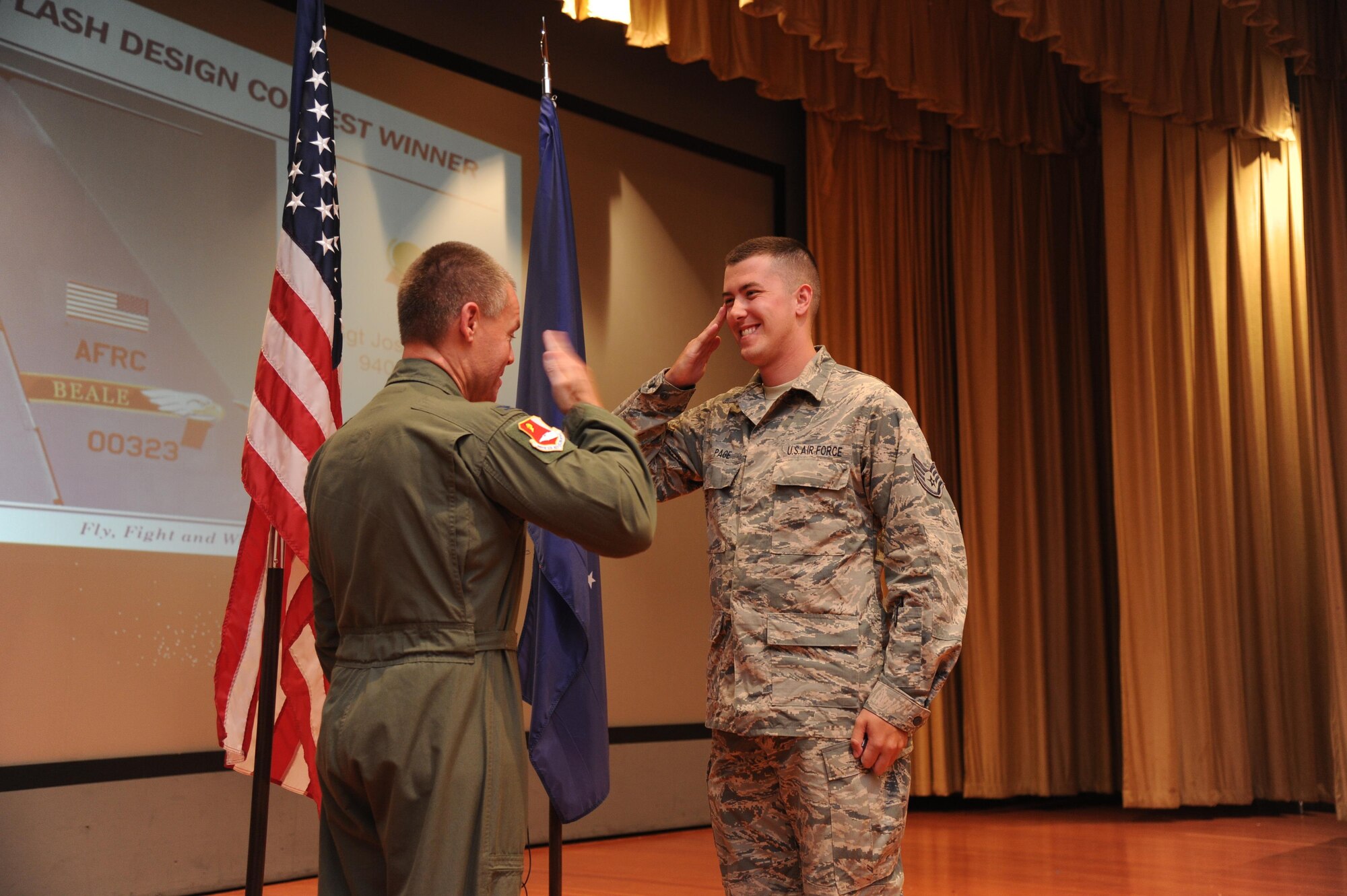 Staff Sgt. Joshua Page, member of the 940th Air Refueling Wing Aircraft Maintenance Squadron, accepts a coin from Col. Craig Peters, 940th Air Refueling Wing commander, for winning the wing tail flash design contest during a Commander's Call at Beale Air Force Base, California on August 7, 2016. Page was recognized for his original design concept incorporating the historical colors of the wing patch into his design and unique local tie with the Sutter Buttes.(U.S. Air Force photo by Tech. Sgt. Heather Skinkle)