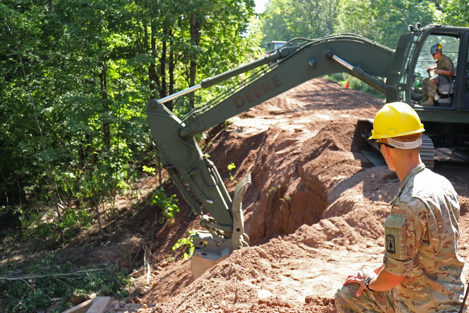 1st Lt. Joshua Steadman supervises Spc. Michael Baldwin, both members of the 229th Engineer Company, while using an excavator to backfill a washed-out culvert along Eade Road in Ashland County, Wisconsin Aug. 9, 2016, as part of flood recovery operations. 