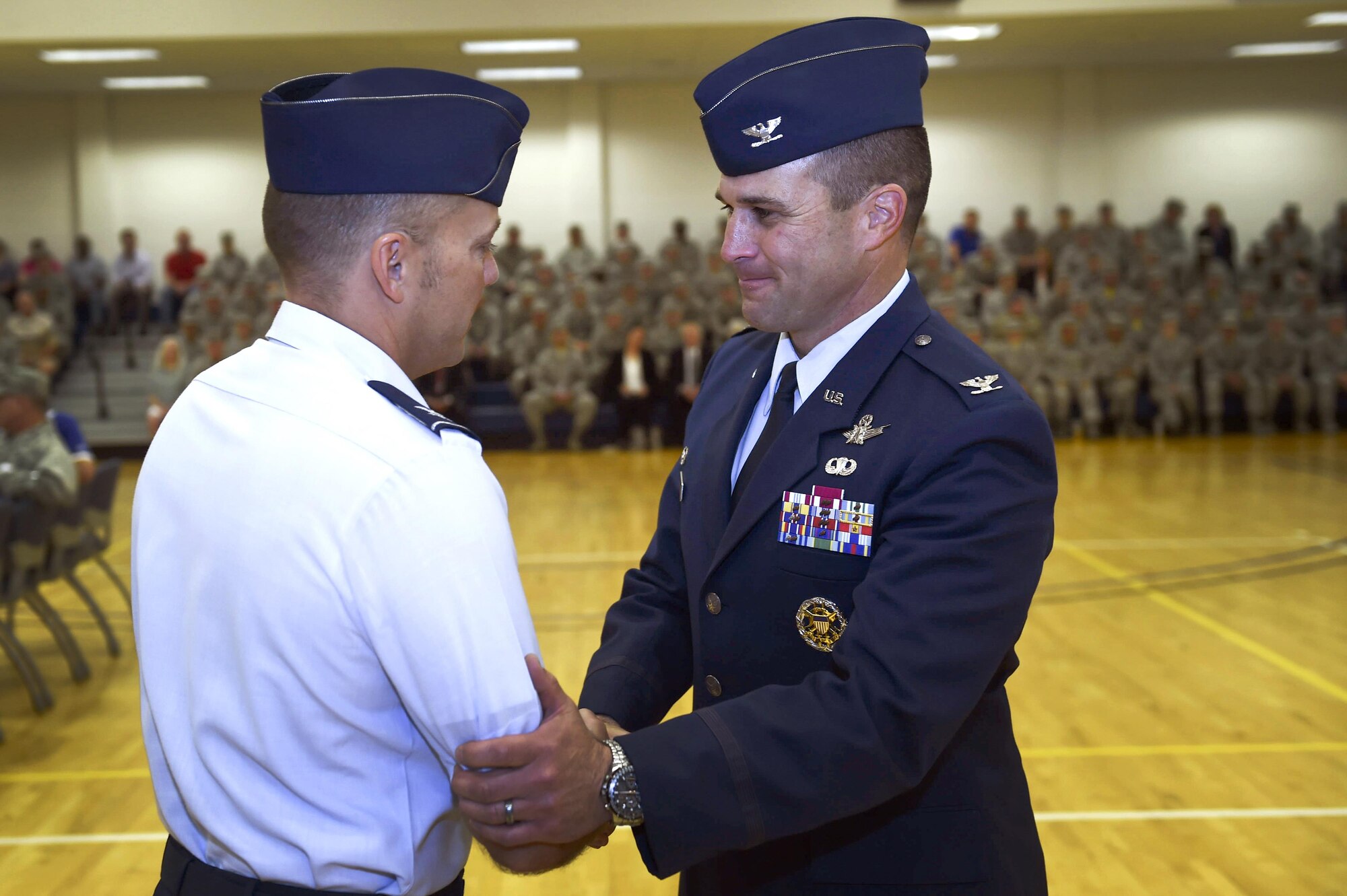Col. John Wagner, outgoing 460th Space Wing commander, bids farewell to Col. Scott Romberger, 460th Space Wing vice commander, during the 460th Space Wing change of command ceremony at the Buckley Fitness Center on Buckley Air Force Base, Colo. The change of command ceremony represents the formal passing of responsibility, authority and accountability of command from one officer to another. (U.S. Air Force photo by Airman Holden S. Faul/Released)