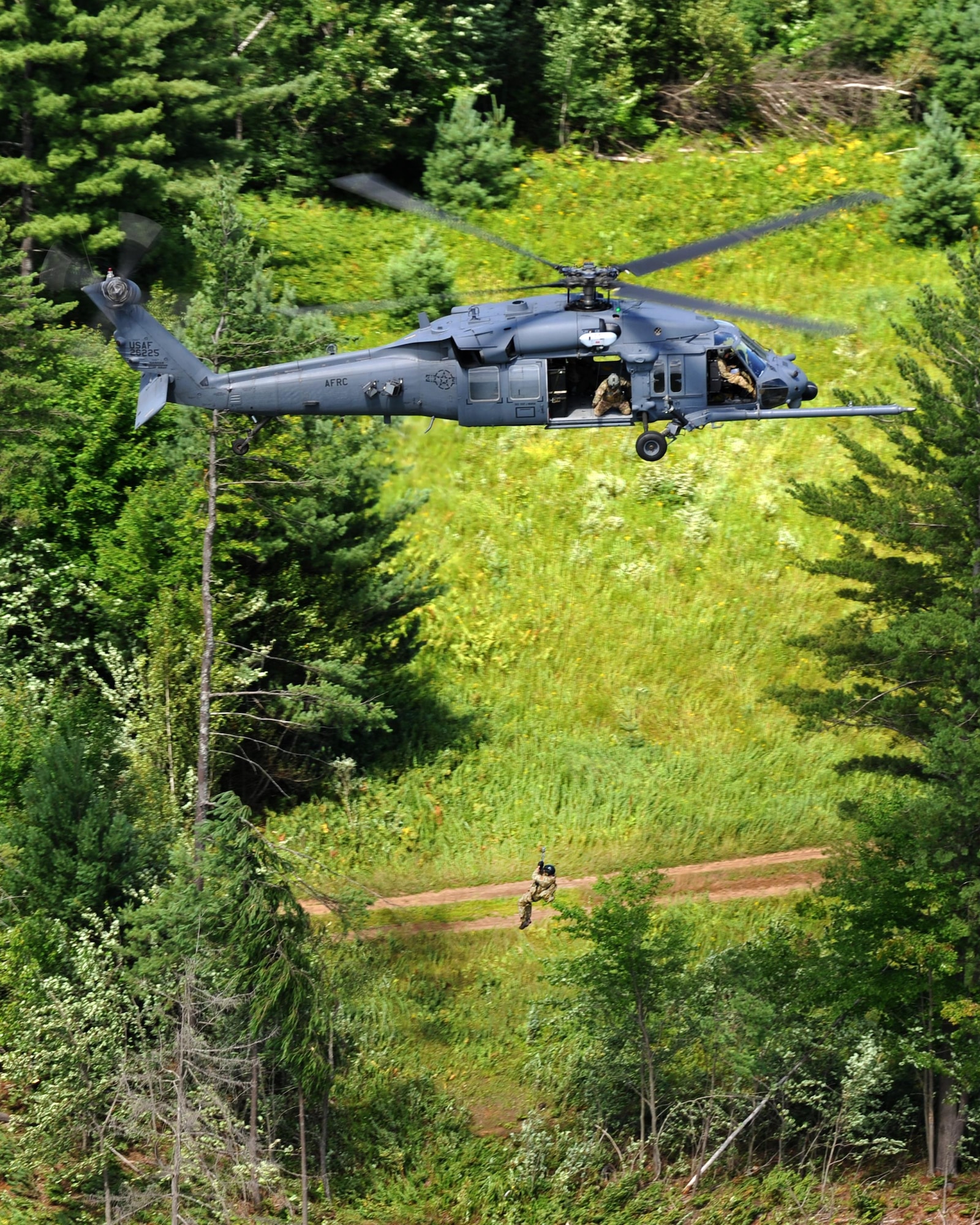 Air Force Reserve aircrew from the 943rd Rescue Group at Davis-Monthan Air Force Base, Ariz., hoist (simulated) crash "survivor" Capt. Clay Shaner, an F-16 pilot from the 158th Fighter Wing, Vermont Air National Guard, out of the woods during a combat search and rescue training flight in upstate New York Aug. 2. Approximately 50 Air Force Reserve Airmen from the 943rd Rescue Group deployed for training to the East coast for joint operations July 31 to Aug 12. (U.S. Air Force photo by Carolyn Herrick)