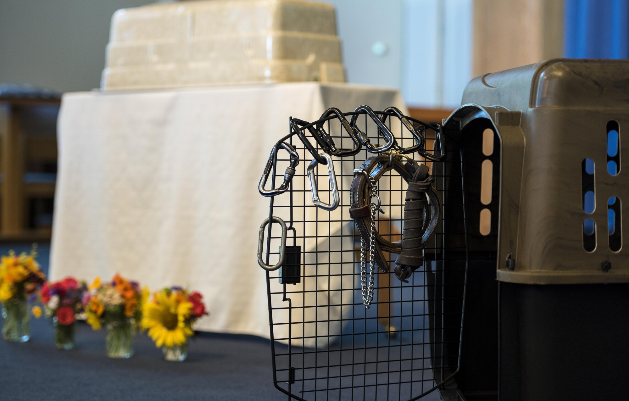 366th Security Forces Squadron military working dog handlers hang their carabiners on fellow working dog Vvass' kennel during the memorial ceremony Aug. 11, 2016, at Mountain Home Air Force Base, Idaho. The handlers personalized how they paid respect to Vvass compared to the traditional lying of the badge. (U.S. Air Force photo by Senior Airman Jeremy L. Mosier/Released)