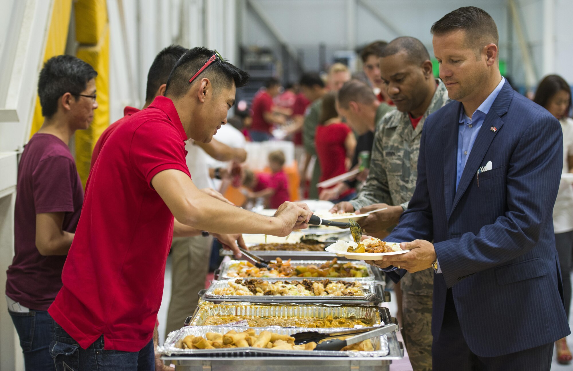 (From the right) Mountian Home Mayor Rich Sykes and 366th Fighter Wing Command Chief Master Sgt. David Brown receive food in a serving line at the Peace Carvin V National Day Celebration. The celebration included a parade of troops, an authentic Singaporean dinner and a cake-cutting ceremony involving both the base and local community. (U.S. Air Force photo by 2nd Lt. Kippun Sumner/Released)
