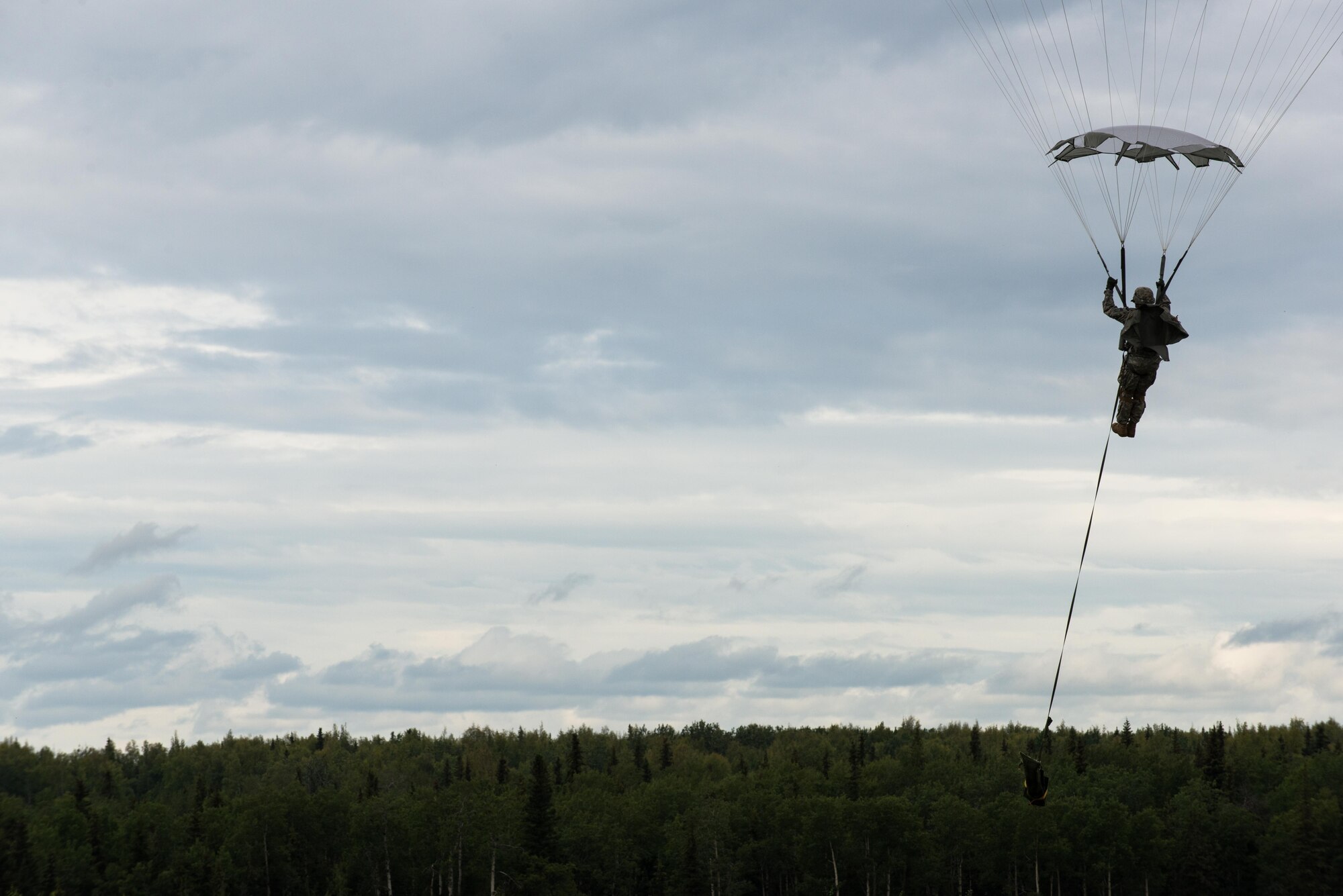 A U.S. Army paratrooper prepares to land after performing an airborne insertion from a C-130 Hercules during Red Flag-Alaska at Joint Base Elmendorf-Richardson, Alaska, Aug 10, 2016. Red Flag-Alaska is an exercise that provides joint offensive counter-air, interdiction, close air support and large force employment training in a simulated combat environment. (U.S. Air Force photo by Staff Sgt. Michael Smith/Released)
