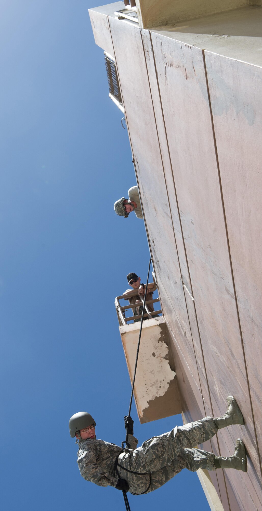 Senior Airman Garrett Hays, 554th RED HORSE Squadron electrical power production, rappels down a 90-foot  tower at Naval Base Guam Aug. 9, 2016. U.S. Navy Petty Officer 1st Class Erickson, parachute rigger and U.S. Air Force Master Sgt. Ronald Weymer, 554th RHS team superintendent/rappel master observed for proper techniques and safety. (U.S. Air Force photo by/Master Sgt. JT May III)