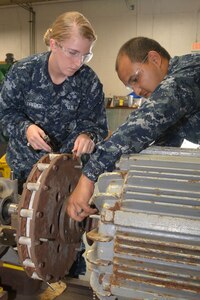 Machinist Mate 1st Class (SW) Raul Coronado demonstrates attaching the laser to the motor shaft ona fire pump to Machinist Mate 3rd Class Brittany Alldredge. High-tech tools like laser alignment systems allow SERMC Sailors to quickly, easily and accurately align pump shafts, adding years to their service life. Photo by Scott Curtis.