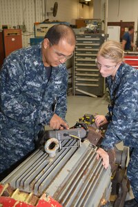 Machinist Mate 1st Class (SW) Raul Coronado explains the visual data collected by the laser sensor on a firemain pump to Machinist Mate 3rd Class Brittany Alldredge. The graphic display takes the guesswork out of shaft alignment and ensures the shafts of the motor and pump are properly aligned, or "co-linear." Photo by Scott Curtis.