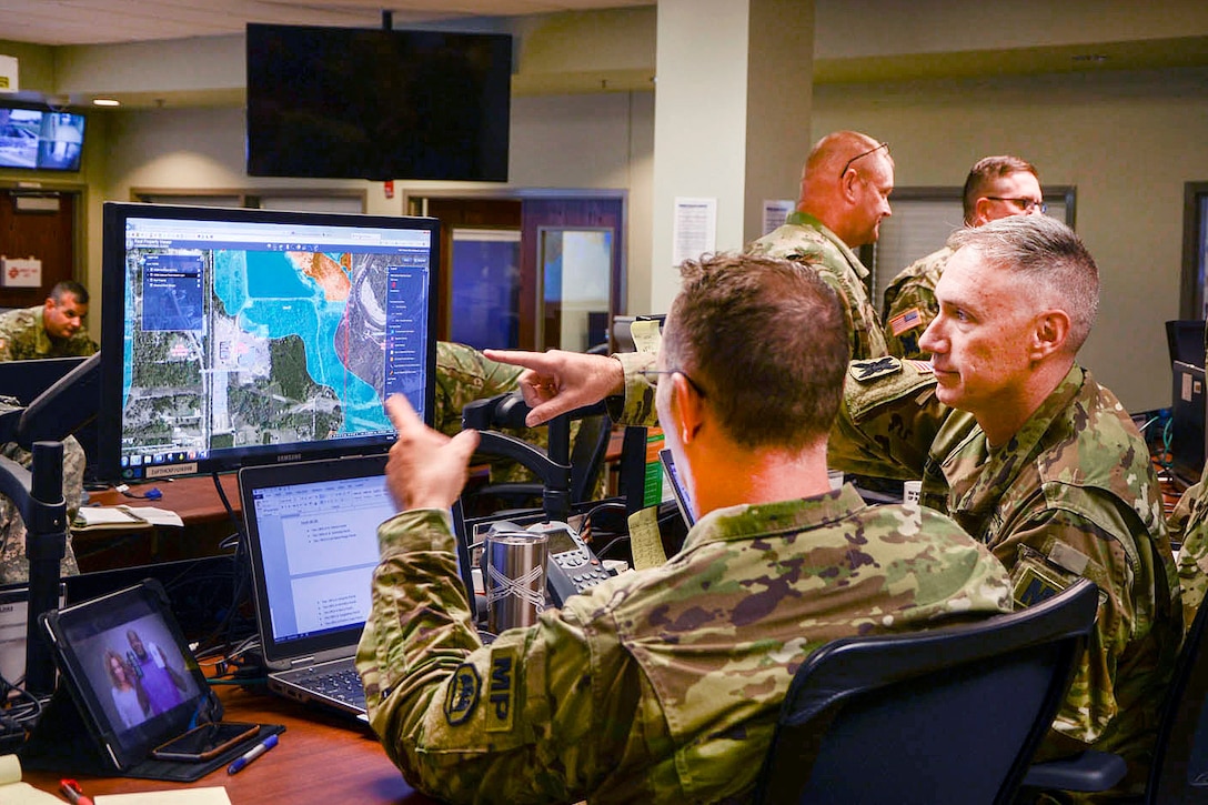 Army Lt. Col. Travis Douget, left, and Army Capt. Chad Goynes discuss operations at Louisiana National Guard’s joint operations center at Camp Beauregard in Pineville, La., Aug. 13, 2016. The center manages incoming missions and resources as the Guard responds to the heavy flooding in southern Louisiana. Army National Guard photo by Sgt. Noshoba Davis 