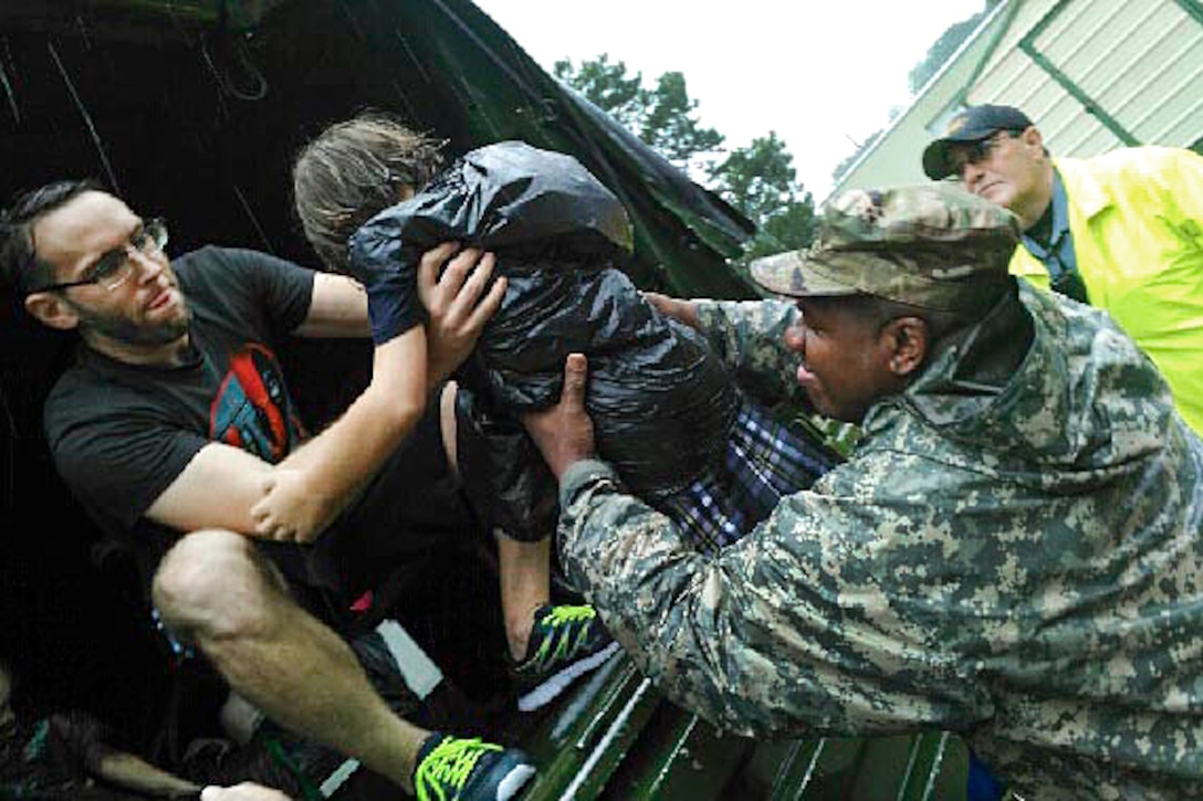 Army 1st. Sgt. Bruce Jackson, right, lifts four-year old Zoe Trappey to her parents during flood relief operations in Lafayette, La., Aug. 13, 2016. Jackson is assigned to Company C, 769th Brigade Engineer Battalion, 256th Infantry Brigade Combat Team. The Louisiana National Guard has mobilized more than 1,000 personnel following heavy flooding. Army National Guard photo by Staff Sgt. Greg Stevens 
