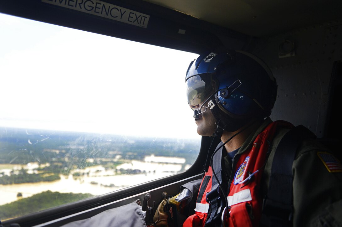 A Coast Guard crew chief surveys the flood waters from a MH-65 Dolphin helicopter over Baton Rouge, La., Aug. 14, 2016. The Coast Guard assisted victims by land and air. Coast Guard photo by Petty Officer 3rd Class Brandon Giles