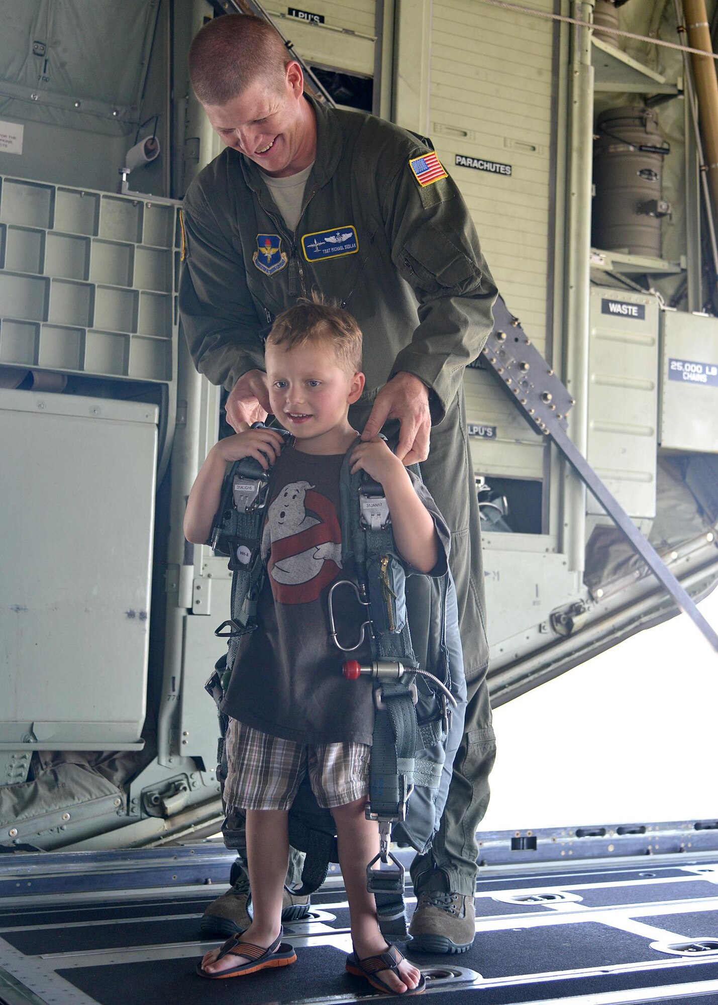 Tech. Sgt. Mike Sedlak sets up Cameron Repasky, 5, with a parachute during the Hearts Apart Youth Deployment Line. The event takes place every year to gives kids from military families an opportunity to learn about the deployment process. (Photo by Todd Berenger)