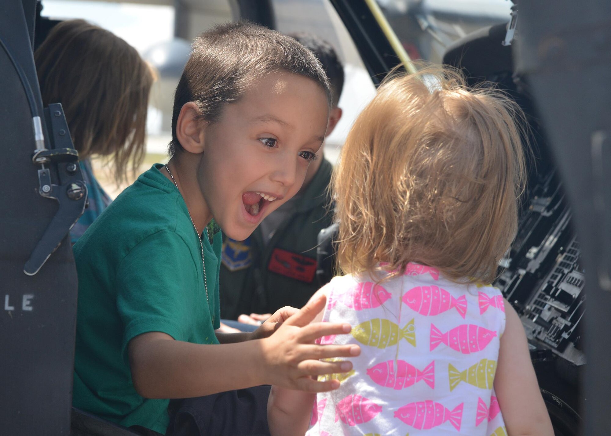 Alex Small, 6, shows his enthusiasm to his sister, Selena, 1, while sitting in the cockpit of a UH-1N Huey helicopter. The kids were participating in the Hearts Apart Youth Deployment Line, an event that takes place every year to gives kids from military families an opportunity to learn about the deployment process. (Photo by Todd Berenger)
